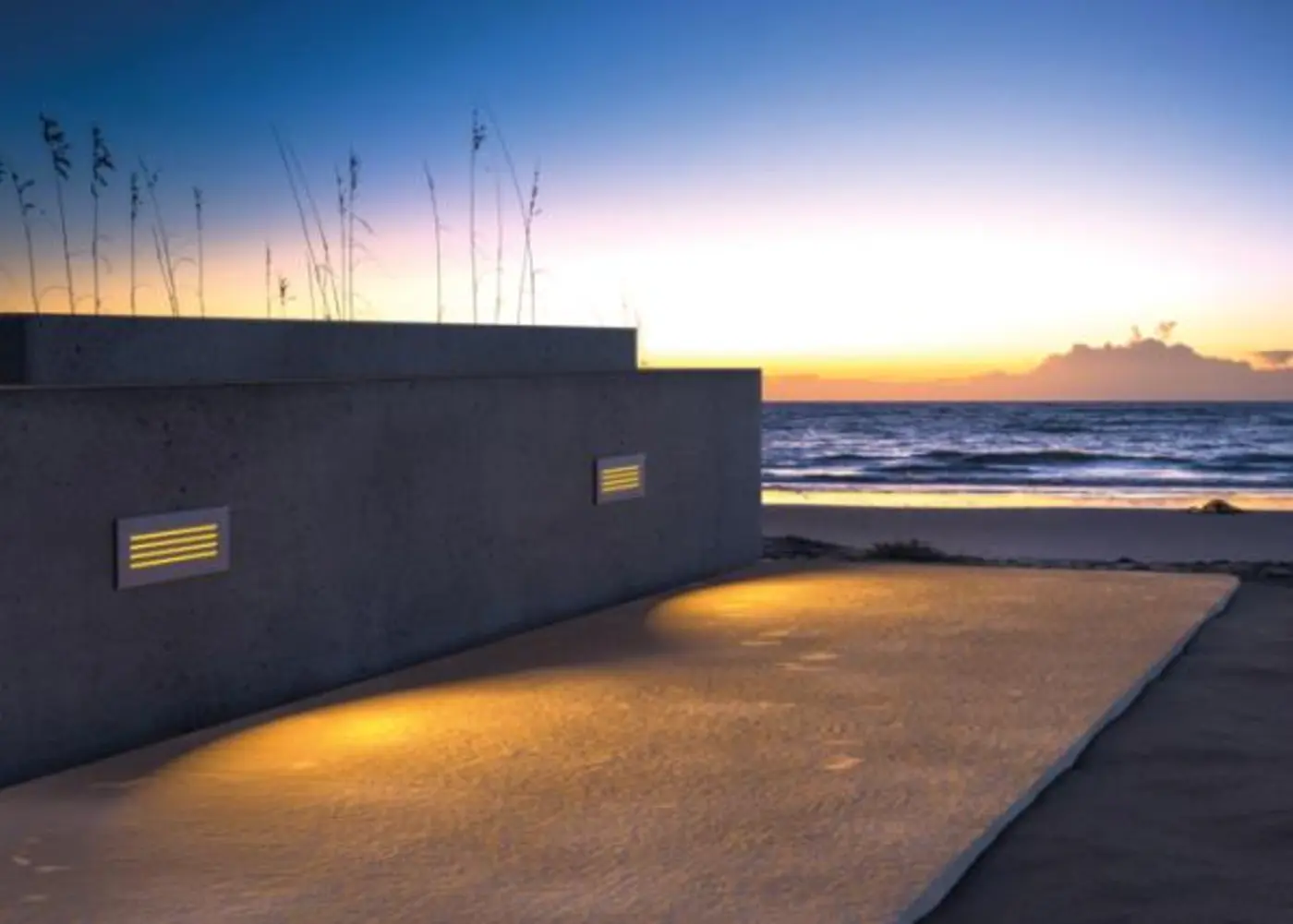 Amber step lights on a beach walkway at dusk