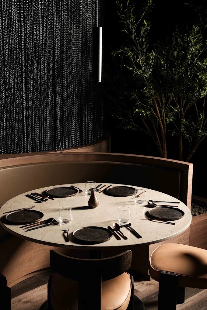Corner booth at Hikari with a slim linear wall light against a chain screen