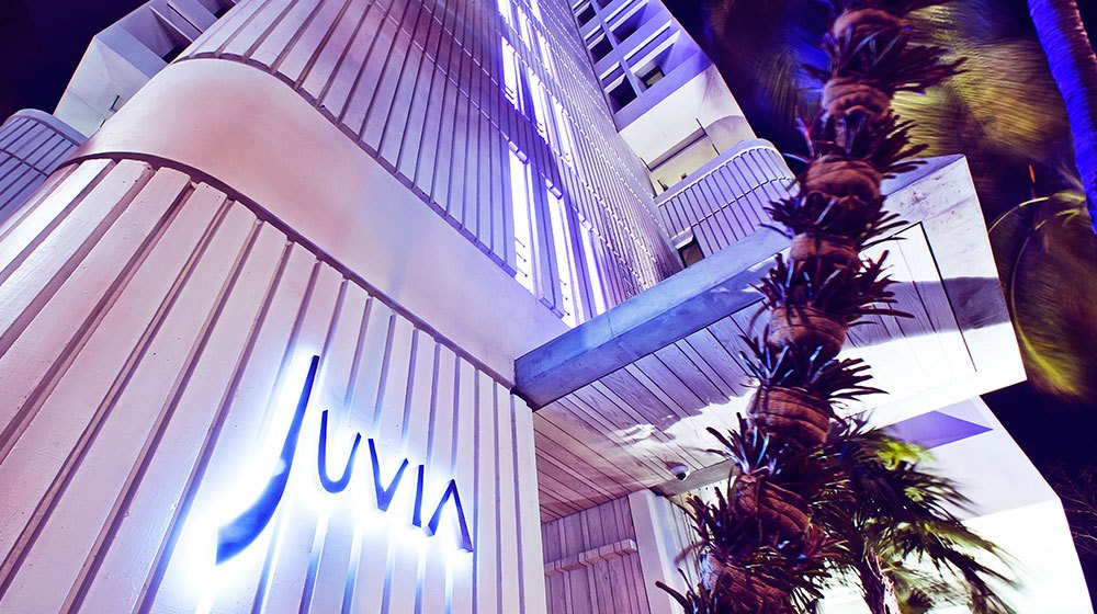 The illuminated Juvia sign and uplit facade at street level