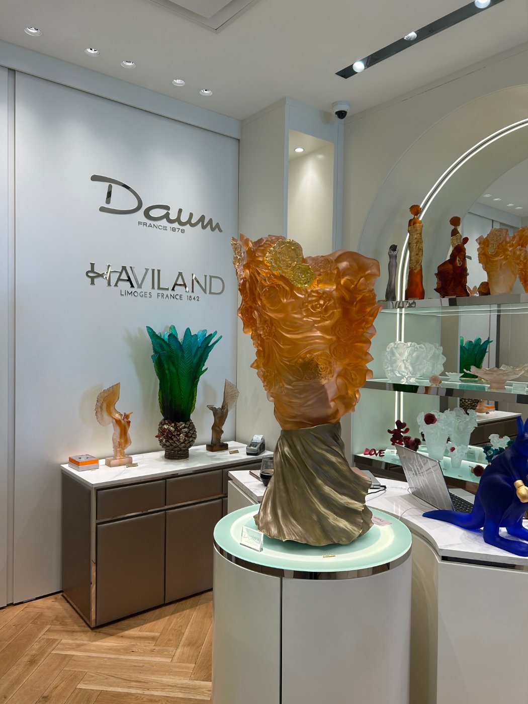 Daum crystal sculpture on a lit plinth beneath the Daum and Haviland signage, with a slim magnetic track overhead