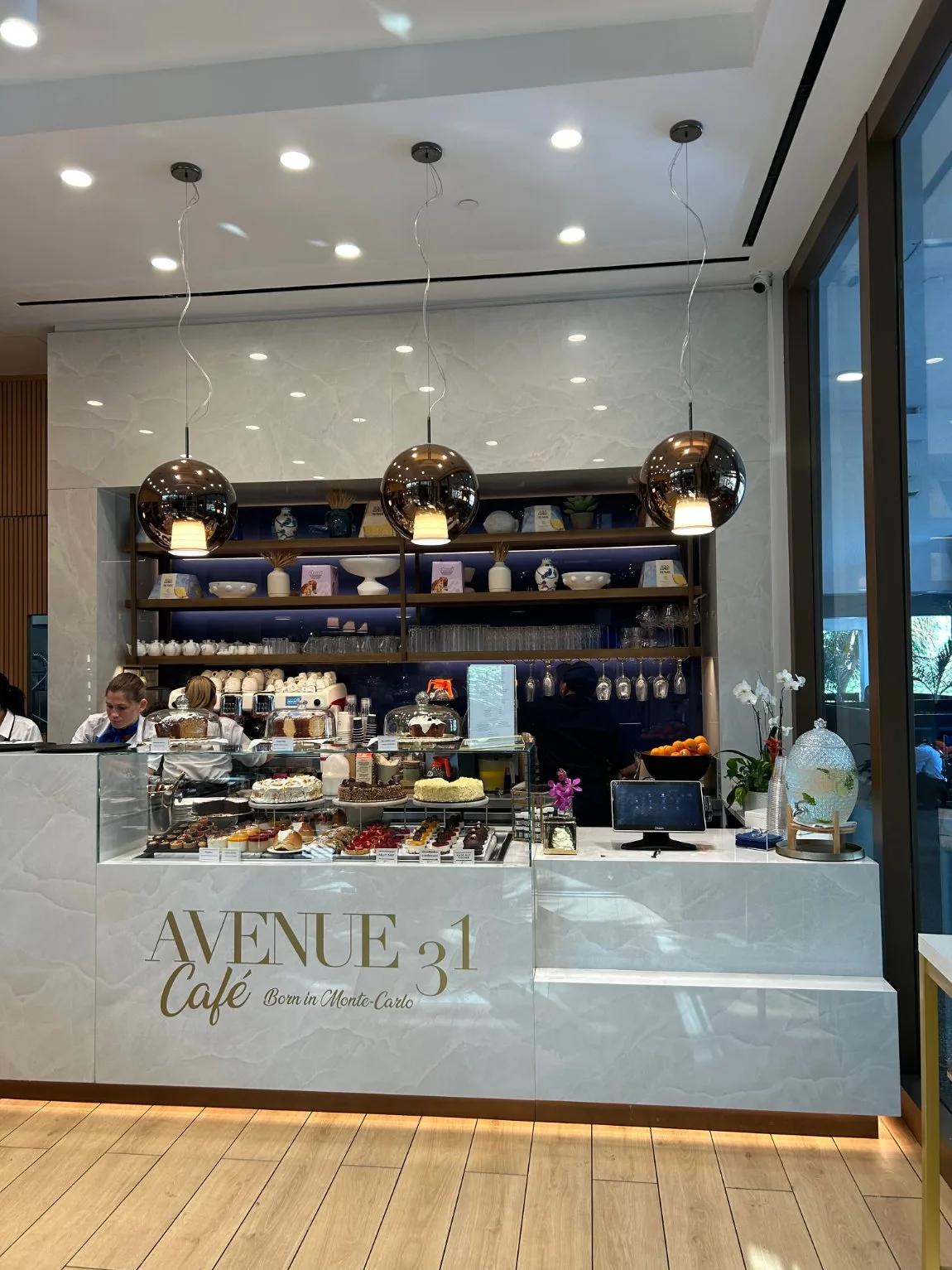 Avenue 31 Cafe at Bal Harbour Shops, with three mirrored copper globe pendants over the pastry counter and internally lit back shelving