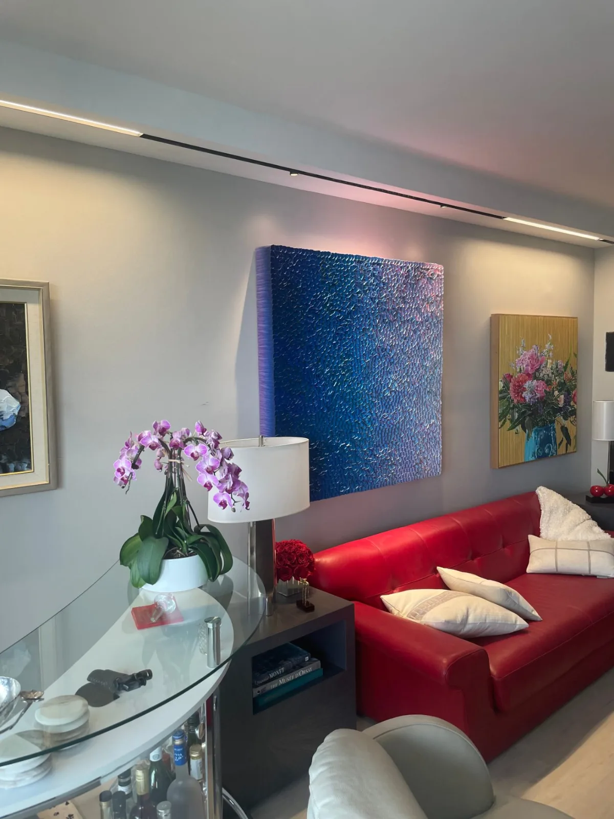Living room at a Williams Island residence with slim linear track lighting across the art wall