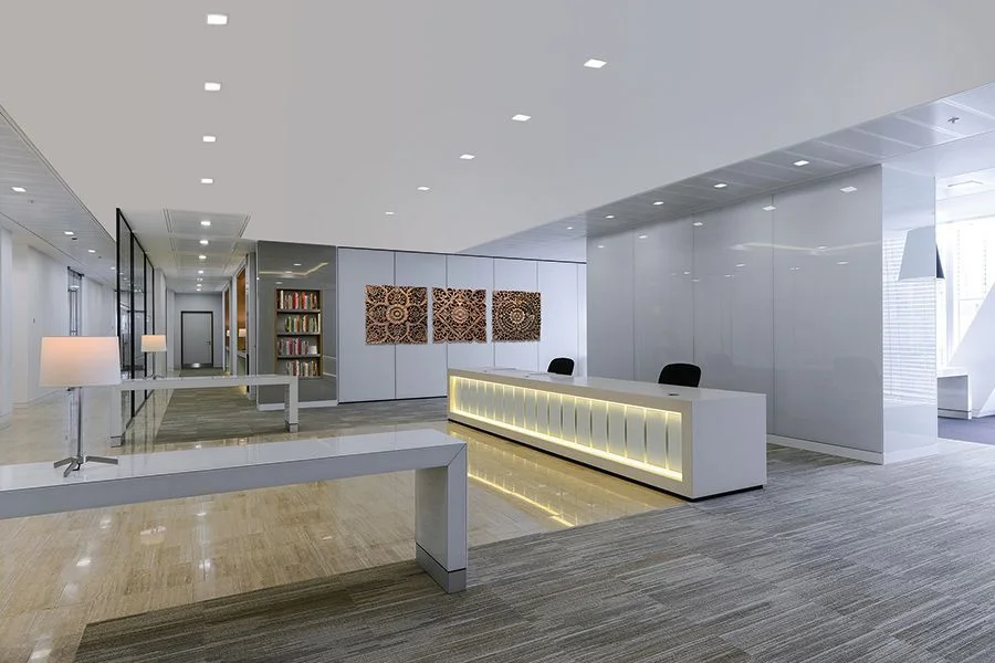 Office reception lit with recessed square-aperture downlights
